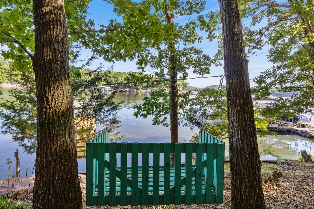 A turquoise bench sits beside a serene lake, surrounded by lush trees that frame the tranquil water. The scene is peaceful and inviting, suggesting opportunities for quiet reflection, picnicking, or simply enjoying the natural beauty that the lake setting offers.