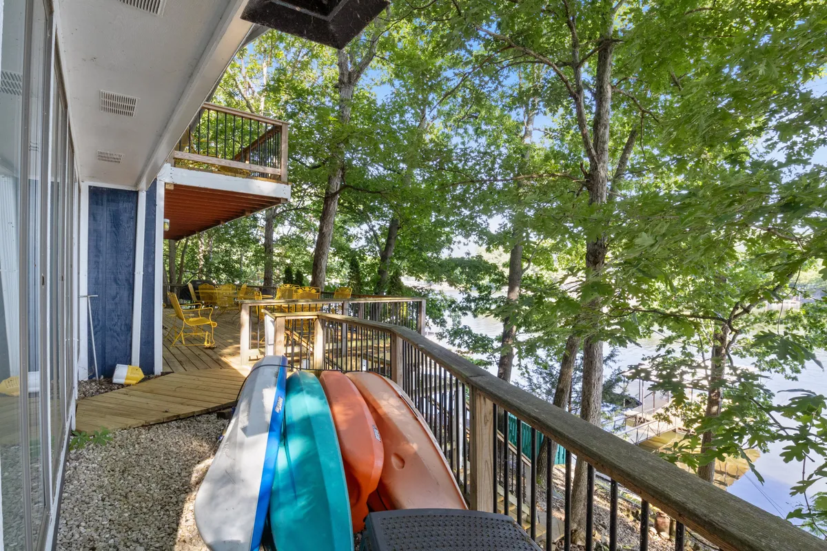 A lakeside deck featuring bright kayaks, inviting deck furniture, and sweeping water views. The scene is set for water activities and relaxing moments close to the lake, emphasizing easy access to water gear and outdoor fun.