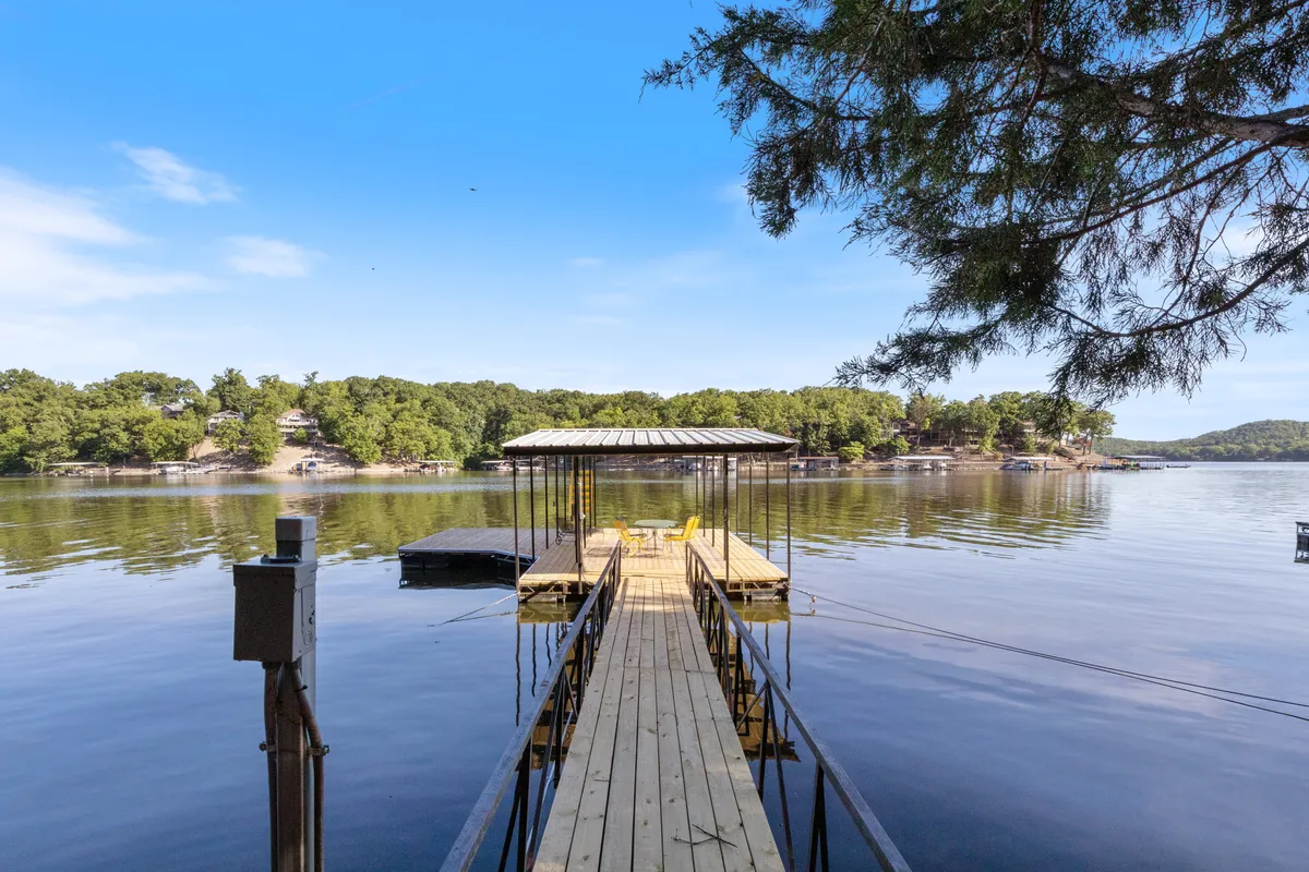 This image captures a serene lakeside dock equipped with yellow chairs set against calm water and lush surrounding trees. The dock is clearly a focal point for water-based activities, and the inviting seating illustrates an ideal spot for relaxing, socializing, and enjoying the waterfront view.