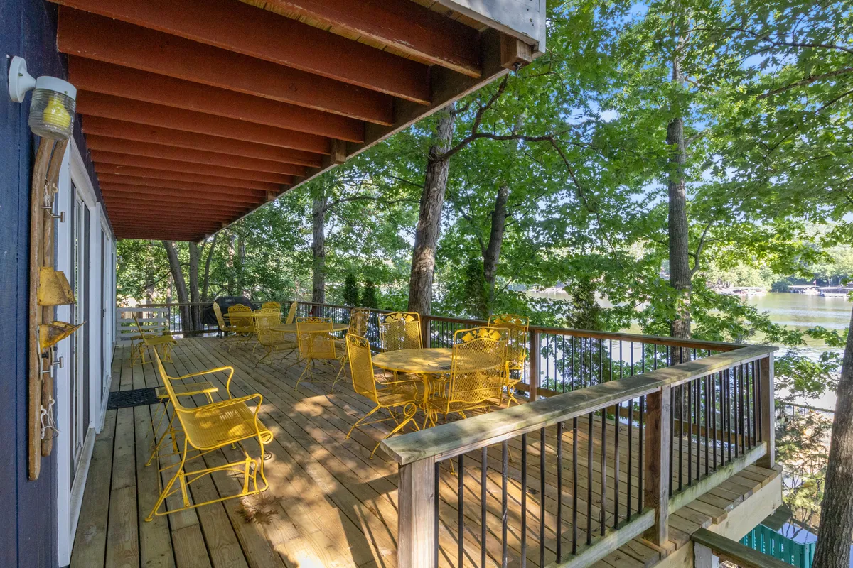 A cheerful wooden deck set with yellow outdoor furniture, surrounded by trees and offering a tranquil water view. The space is perfect for outdoor dining, relaxed gatherings, or enjoying sunrise coffee and starlit dinners.
