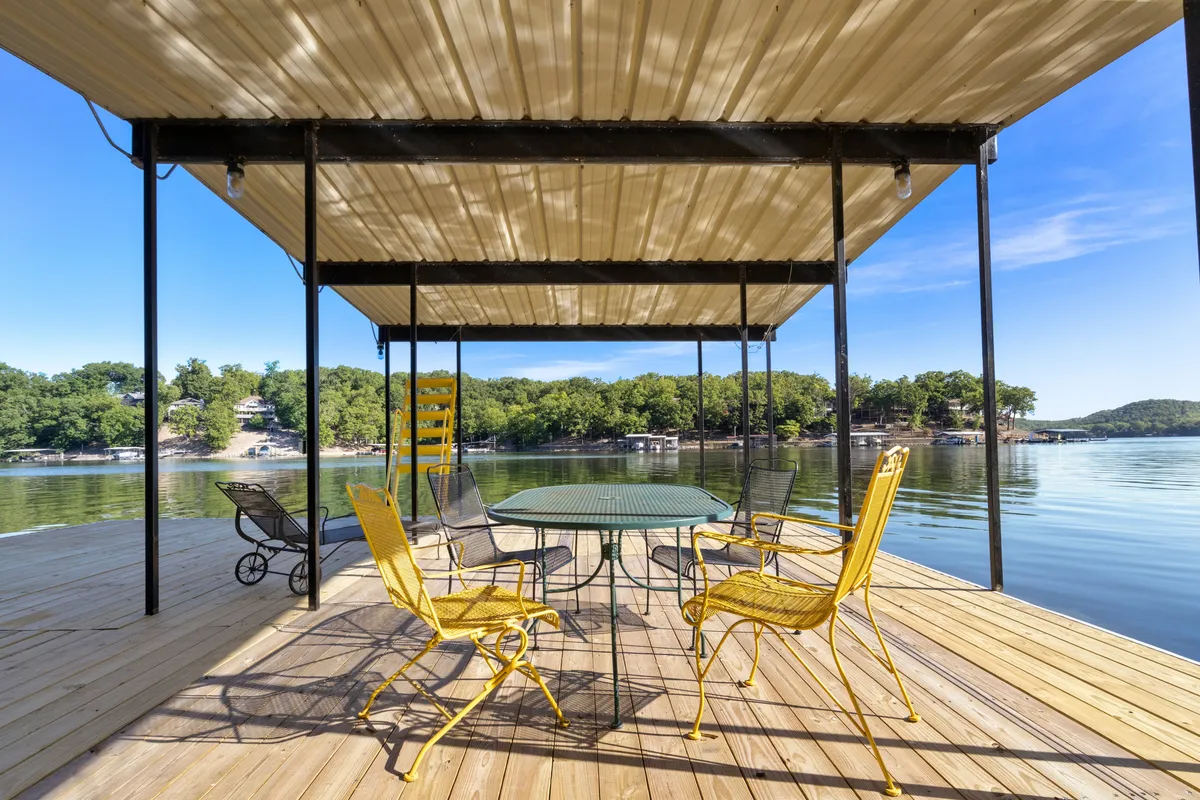 Bright yellow chairs circle a table on the lakeshore, offering a direct view of the shimmering water. The setup is inviting and encourages socializing, dining, or sharing stories with friends and family as you soak in the lake surroundings.